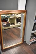 A large 20th-century rectangular wooden-framed mirror, with a gilded frame and arched etching to