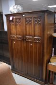 A reproduction oak wardrobe in the Priory style, approx. dimensions H169 W106 D57