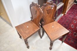 A pair of 19th Century mahogany hall chairs having shaped shield backs and turned front legs
