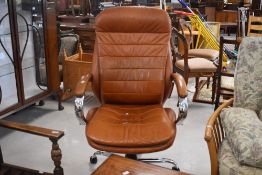 A vintage swivel office chair having chrome frame and tan leather upholstery