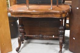 A Victorian walnut and mahogany fold over card table , having shaped top with heavily carved