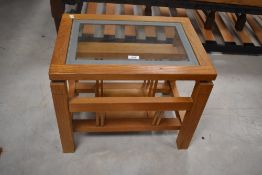 A modern golden oak coffee table having glass insert and magazine rack under, approx. 52 x 37cm