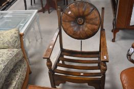 An early 20th Century oak armchair having circular leather back pad