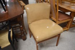 A pair of vintage designer style teak framed dining chairs having overstuffed cream leatherette