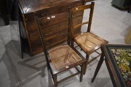 A pair of Edwardian bedroom chairs having inlay decoration and canework seats