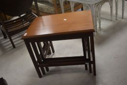 A vintage nest of three teak effect and mahogany occasional tables, width approx. 55cm