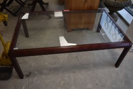 A vintage glass top coffee table having mahogany effect stained frame, dimensions approx. 130 x 80 x