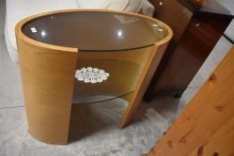 A modern Tom Schneider console table of elliptical form , with glass top and undershelf, natural