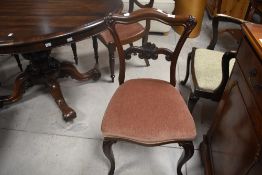 A set of six Victorian rosewood/mahogany balloon and rail back dining chairs having drop in seats