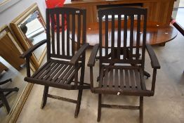 A pair of teak folding garden chairs, dark stained