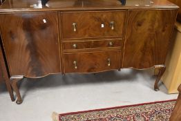 An early 20th Century walnut sideboard having three central drawers, flanked by cupboard, and having