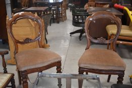 A pair of Victorian mahogany balloon back dining chairs having overstuffed seats and later beige