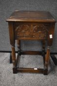 A carved oak side table with flip top lid and inner storage space.