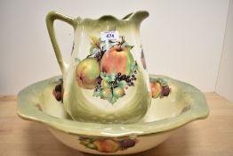 A water jug and bowl in green and cream hues and having orchard fruit design.