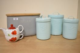 A ceramic bread bin having raised 'Bread' wording, three vintage enamel storage canisters with lids,