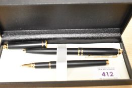 A boxed matte black and gold ballpoint and rollerball pen set