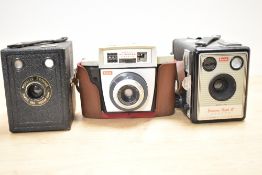 A collection of three Kodak cameras, a Kodak Autosnap camera, a Kodak Brownie Flash III box