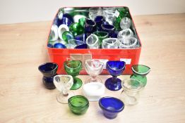 A collection of 19th century eye wash cups, including coloured glass and ceramic examples.
