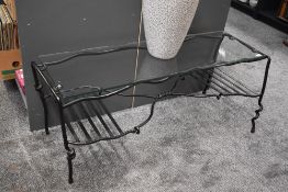 A contemporary wrought iron glass-top coffee table, featuring a twisted and expressive frame,