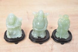 A selection of three 20th-century Chinese carved green-stone figurines, possibly jade, all on wooden