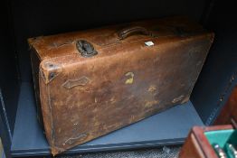 An early 20th century leather bound suitcase in mid brown textured leather with stitched corners.