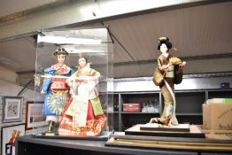 A group of three Korean costume dolls, two inside a plastic display cabinet.
