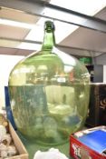 A large Victorian green glass carboy with original glass stopper, featuring a short tapering neck