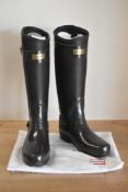 A pair of Hunter tall wellington boots in dark chocolate brown, rubber upper and grip sole,