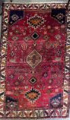 A 20th century vintage Persian wool rug having an abrashed red ground, brown central geometric