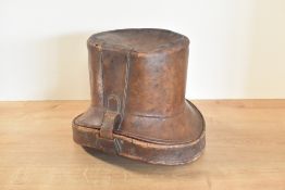 An antique top hat box in brown leather with brass hardware, lined with green velvet, containing a