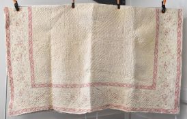 An antique Durham quilt in cream-yellow with a pink floral border design, featuring classic