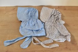 Two cotton bonnets, one in a pink and purple floral stripe fabric and a baby blue example.