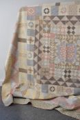 An antique patchwork quilt, with central diamond design in pale ditsy floral fabrics, with red