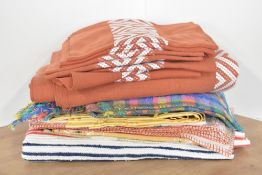 Assorted woven and needlework home linens to include a set of terracotta tablecloths and place