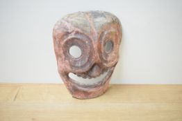 An unusual carved and stained wooden grotesque tribal mask, formed with stylised and distorted
