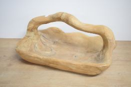 A carved and shaped hardwood fruit basket, of asymmetrical form with integral over handle,