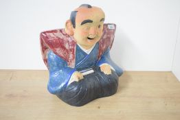 An interesting Japanese part-glazed pottery Fukusuke doll, formed as a seated jolly gentleman in
