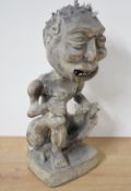 An interesting Indonesian carved wooden figure of a seated, naked emaciated grotesque, modelled