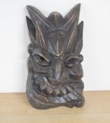 A decorative Chinese carved wooden mask, carved in high relief with grotesque features, 26.5cm
