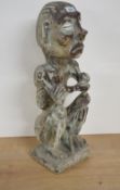 An interesting Indonesian carved wooden figure of a seated, naked emaciated grotesque, modelled