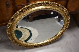 A reproduction gilt frame wall mirror of oval form, width approx. 75cm