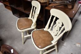 A pair of painted fiddle back kitchen chairs having padded leather seats and turned frames