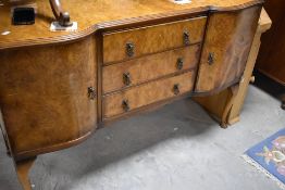 An early to mid 20th Century walnut sideboard having central drawers flanked by cupboards, on