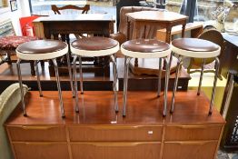 A set of four vintage stools, having vinyl seats, plastic rims and chrome legs