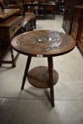 A Victorian occasional table in the gypsy style having carved circular top and undertier on triple