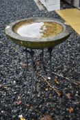 An ornamental concrete bird bath on metal stand