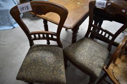 A pair of Victorian dining chairs having bobbin turned rail back and overstuffed drop on seats