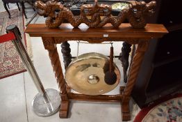 An Indonesian hardwood framed brass gong having carved mythical creature decoration