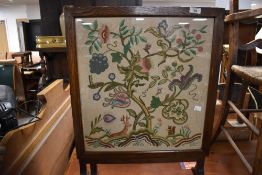 A traditional oak fire screen table having embroidered panel