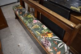 A traditional oak church pew having later upholstered seat with wildlife theme, length approx.
